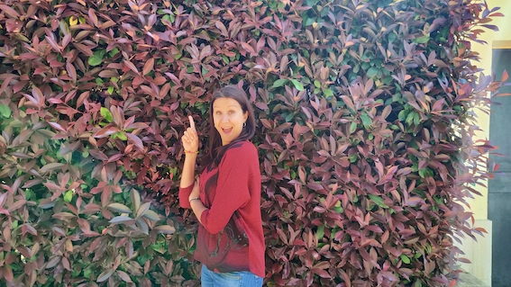 A woman posing in front of a wall of plants with startup support.