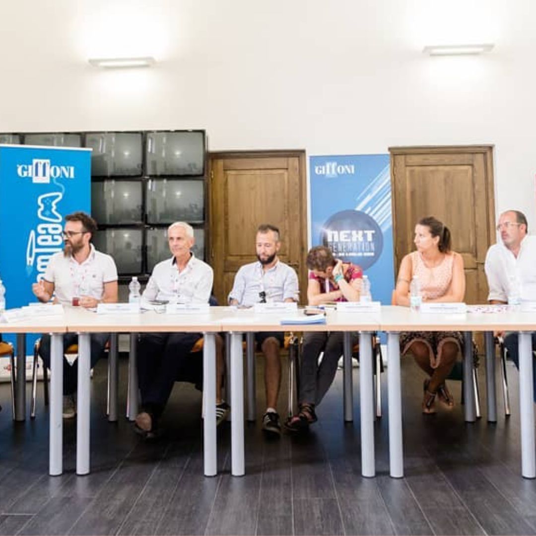 A group of entrepreneurs sitting at a long table, receiving support from a marketing coach within their startup community.