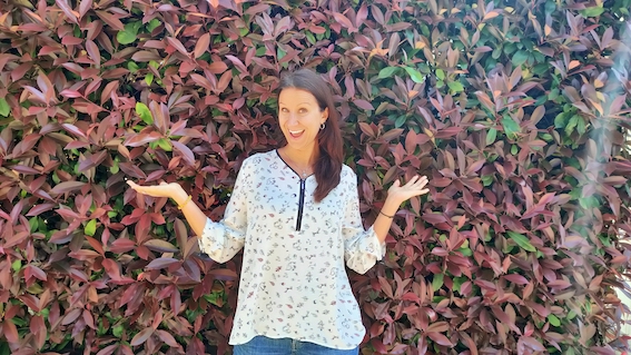 A woman posing in front of a bush, symbolizing entrepreneurial and startup support.