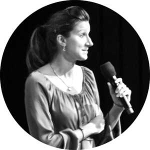 A black and white photo showcasing a woman confidently holding a microphone, representing the powerful presence in the startup community.