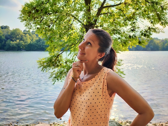 A woman standing near a lake, contemplating her entrepreneurial journey with the support of a startup coach.