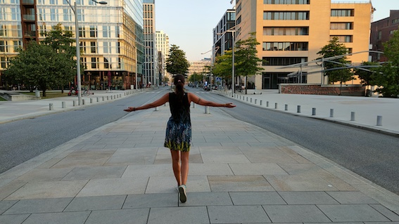 A woman standing on a city street with her arms outstretched, receiving startup support and marketing support from a dedicated startup coach.