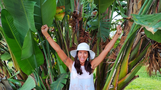 A woman in a white hat standing in front of a banana tree, exuding entrepreneurial spirit as she receives support from the startup community.
