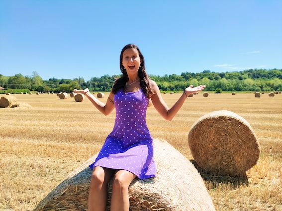 A woman sitting on hay bales in a field, seeking entrepreneur support and startup support.