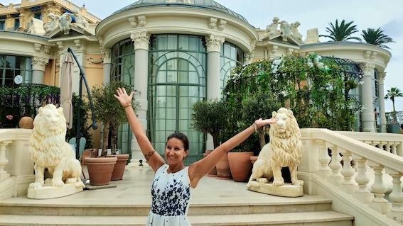 A woman receiving startup support while standing in front of a mansion with lion statues.