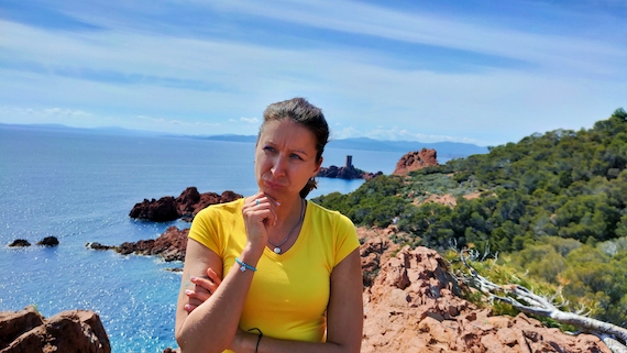 A woman standing on a rocky cliff overlooking the ocean, finding solace and inspiration in the vastness of the unparalleled startup community.