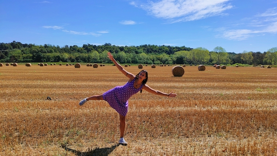 A woman in a dress standing in a field with hay bales, offering startup support and entrepreneur support.