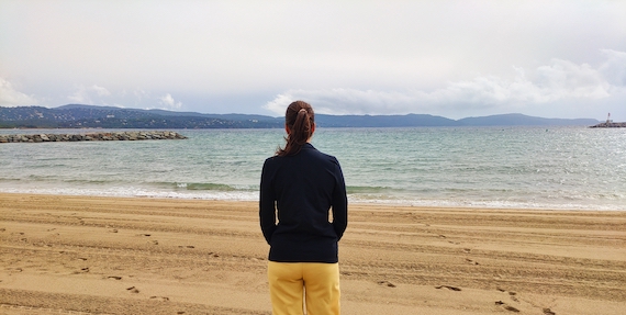 A woman standing on a beach, enjoying the serene view of the ocean.