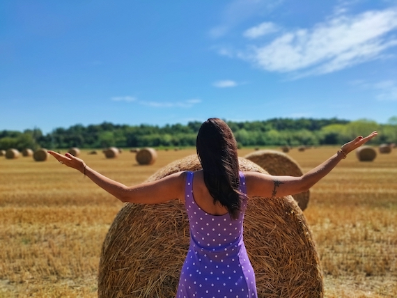 An aspiring entrepreneur standing in a field with her arms outstretched, seeking startup coach support.