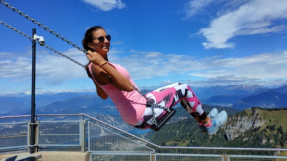 A woman enjoying the thrill of swinging on a swing at the top of a mountain, seeking marketing support.