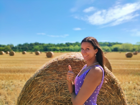 A woman in a polka dot dress standing next to a hay bale, receiving entrepreneur support.