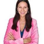 Woman in a pink jacket smiling with arms crossed.