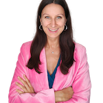 Woman with crossed arms smiling in a pink jacket.