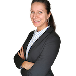 Professional woman in a suit with arms crossed smiling.